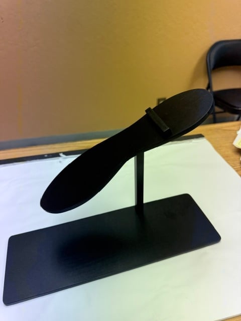Black VR hand controller mounted on a display stand on a desk