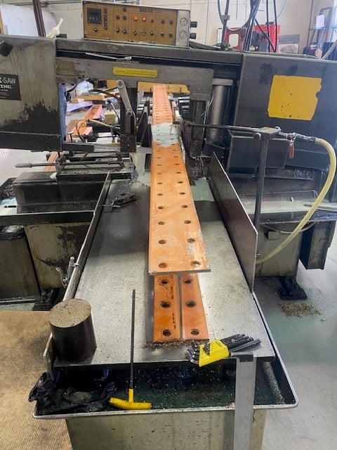 Industrial workshop with wooden beam on testing apparatus, machinery and electrical equipment in background